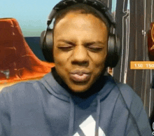 a man wearing headphones and a blue hoodie is making a face .