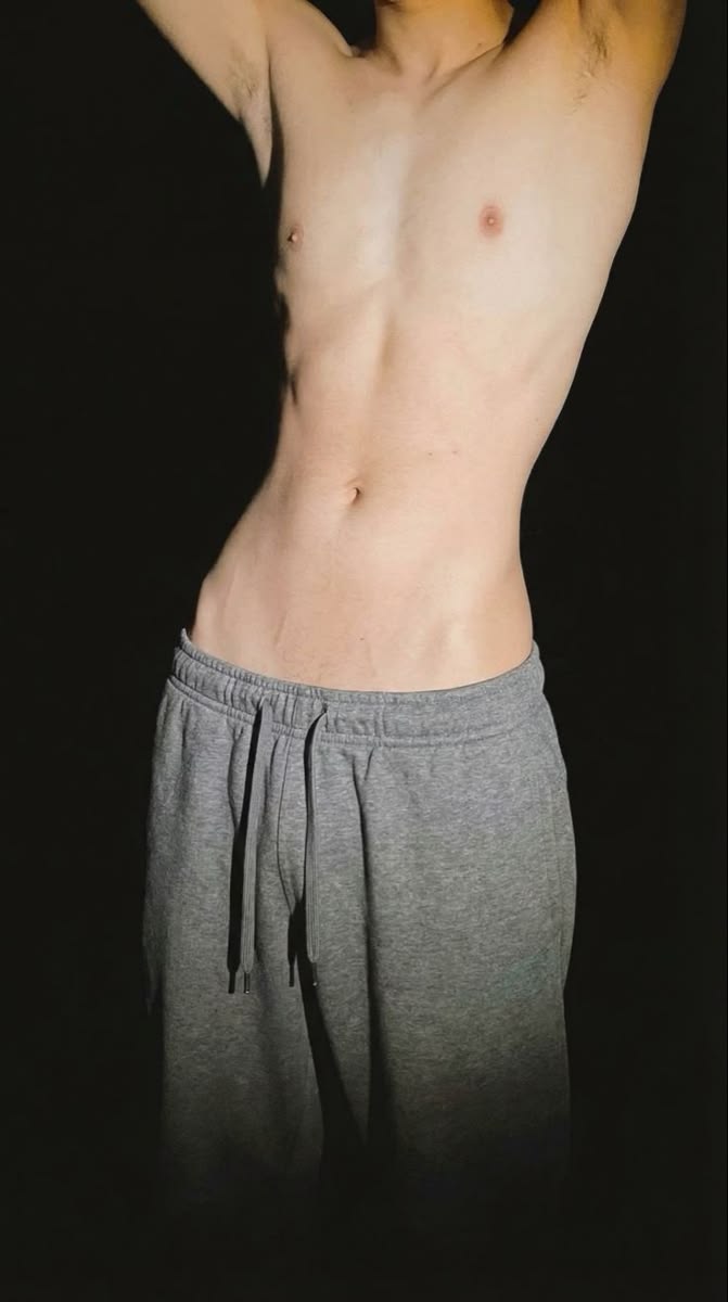 This may contain: a man without a shirt is holding his hand up to his head and wearing sweatpants