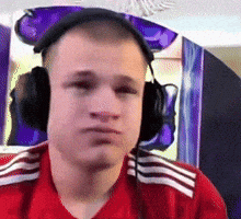 a young man wearing headphones and a red shirt looks at the camera