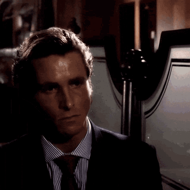 a man in a suit and tie is standing in front of a mirror