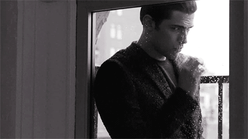 a black and white photo of a man looking out of a window .