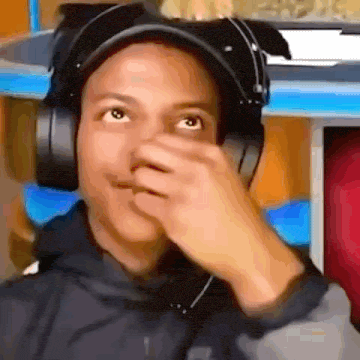 a young man wearing headphones and a hat is covering his nose .