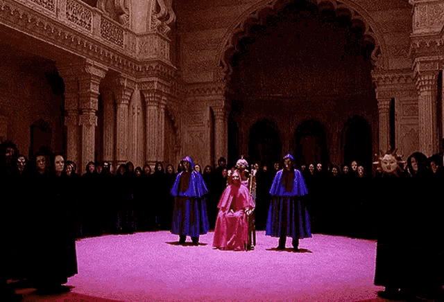 a woman in a red dress is surrounded by people in black