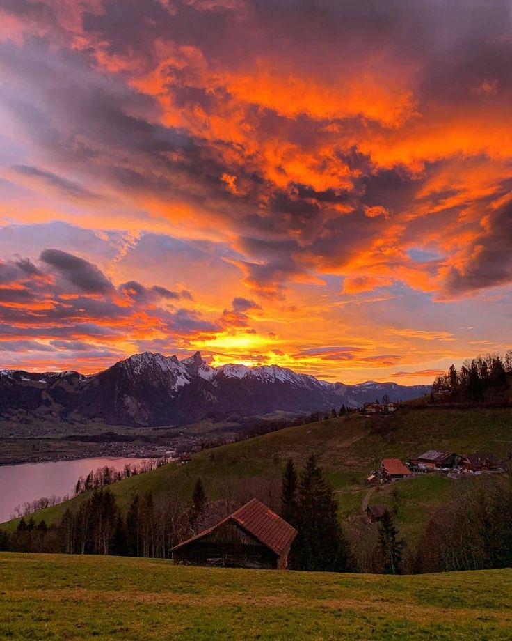 This may contain: the sun is setting over a mountain range with mountains in the distance and houses on the hillside