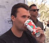 a man drinking from a cup that has a polka dot design on it
