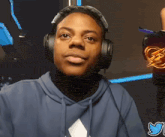 a man wearing headphones looks at the camera with a twitter logo behind him