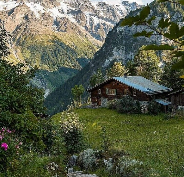 This may contain: a cabin nestled in the mountains surrounded by greenery