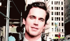 a man in a suit and tie is smiling while standing on a city street .