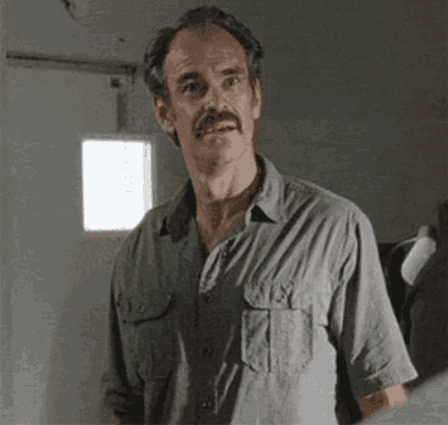 a man with a mustache wearing a gray shirt
