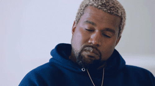 a man with a beard wearing a blue hoodie looks down