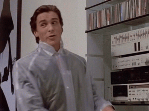a man in a clear plastic jacket is standing in front of a shelf with cds on it .
