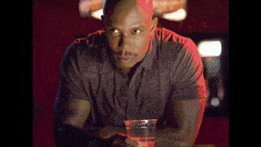a man is sitting at a bar holding a plastic cup of water .