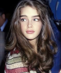 This may contain: a woman with long brown hair and blue eyes