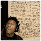 a man wearing headphones stands in front of a wall that has a lot of writing on it