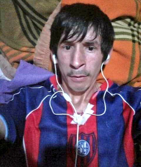 This may contain: a man with headphones on his ears sitting in front of a couch wearing a striped shirt