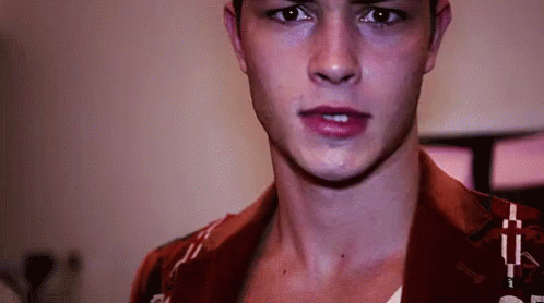 a close up of a man 's face with a red shirt on looking at the camera .