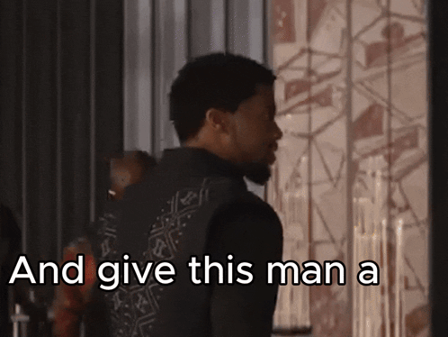 a man standing in front of a wall with the words  and give this man a 