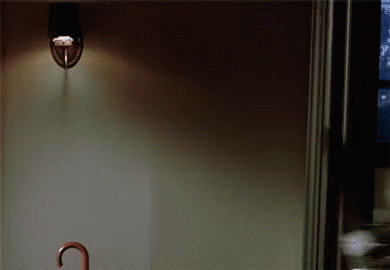 a light is hanging from the ceiling in a dark room with a umbrella in the foreground .