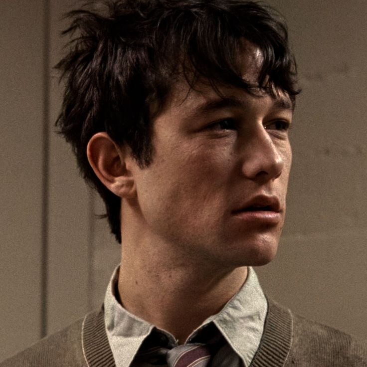 This may contain: a young man wearing a vest and tie looking off into the distance with serious expression on his face