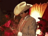 a man wearing a cowboy hat and a suit looks at his phone