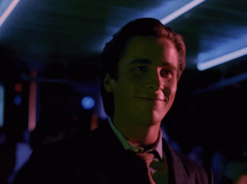 a man in a suit and tie is smiling with a red light behind him