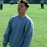 a man in a blue sweater is standing in a field of grass