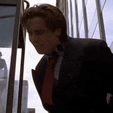 a man in a suit and tie stands next to a phone booth