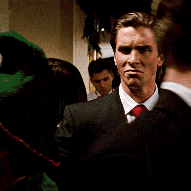 a man in a suit and red tie stands in a crowd of people