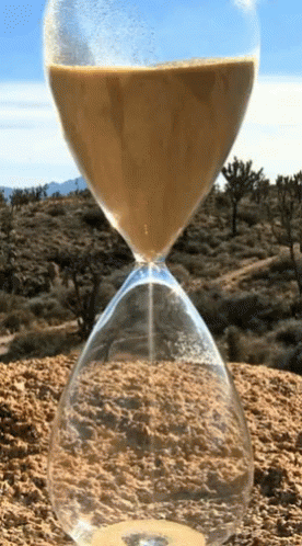 a hourglass filled with sand sits on top of a dirt hill