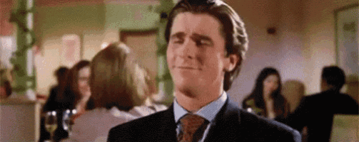 a man in a suit and tie is making a funny face while standing in a crowded room .