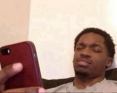 a man is sitting on a couch looking at his cell phone and making a funny face .