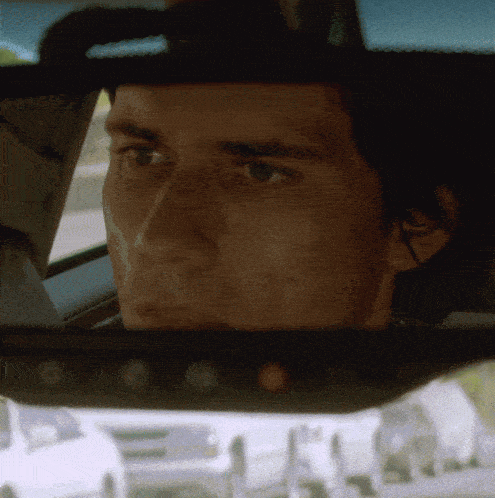 a close up of a man 's face in a car rear view mirror