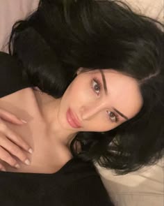 This may contain: a close up of a person laying on a bed with her hand on her stomach