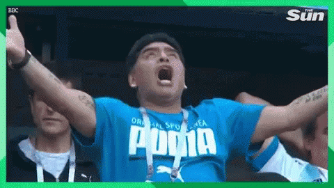 a man wearing a blue puma shirt is screaming in a stadium