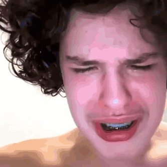 a young man with curly hair is crying with his eyes closed