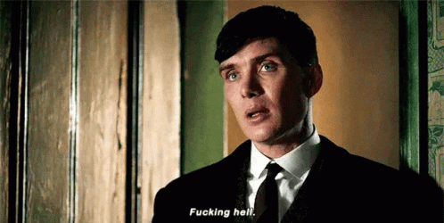 a man in a suit and tie is standing in front of a door and saying `` fucking hell '' .
