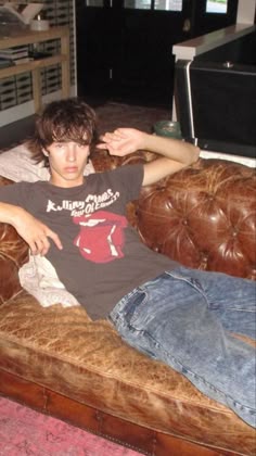This may contain: a young man sitting on top of a brown couch