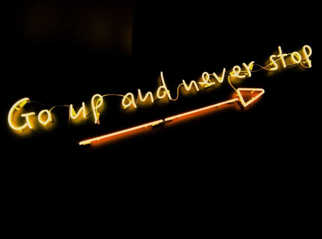 black background with yellow lights saying 'go up and never stop' in reference to personal growth