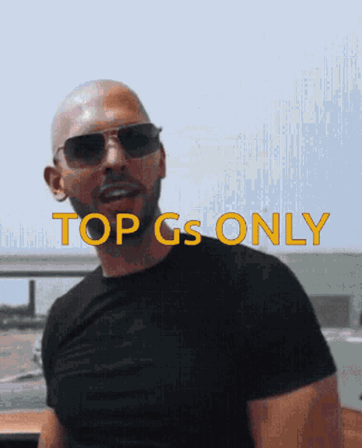 a man wearing sunglasses and a black shirt with the words top gs only on the bottom