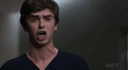 a young man is making a funny face with his mouth wide open .