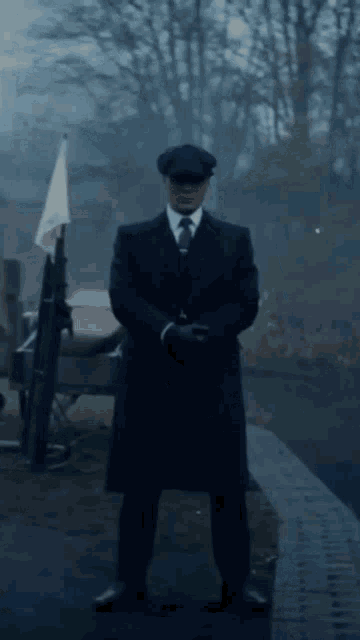 a man in a suit and hat is standing in front of a boat