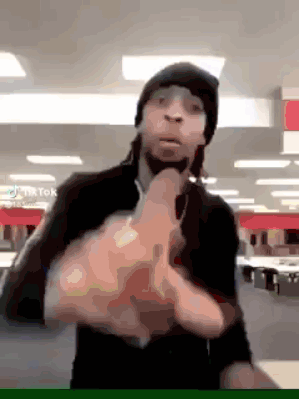 a man wearing a beanie is giving the middle finger in a room .