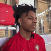 a young man wearing a red shirt with a portuguese flag on it