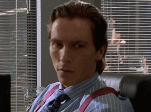 a man in a blue striped shirt and tie is sitting in front of a window