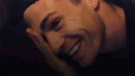 a close up of a man covering his face with his hand while laughing .
