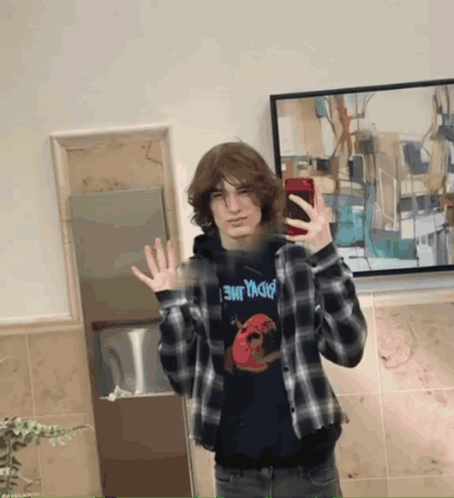 a young man taking a picture of himself in front of a framed painting that says ' badland ' on it
