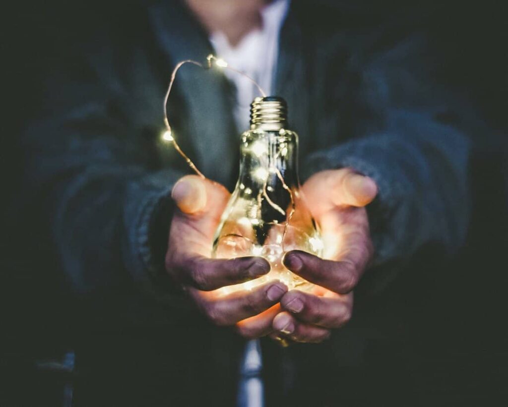 man holding fixed light bulb out to another person