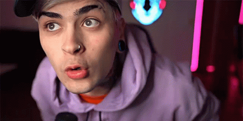 a close up of a person making a funny face while wearing a purple hoodie and a hat .