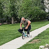 a man is riding a bicycle down a sidewalk in a park .